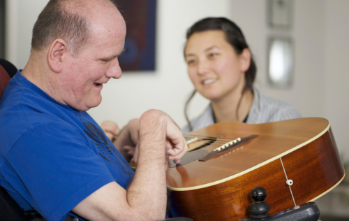 Older guy with IDD playing guitar